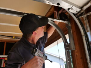 A Million Garage Door Services technician using a drill to repair a garage door opener mechanism in Colorado Springs, CO.