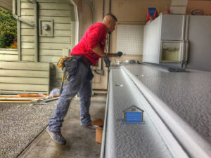 A technician from ETS - Garage Door & Electric Gate Repair Of Bellevue, WA, working on a garage door panel.
