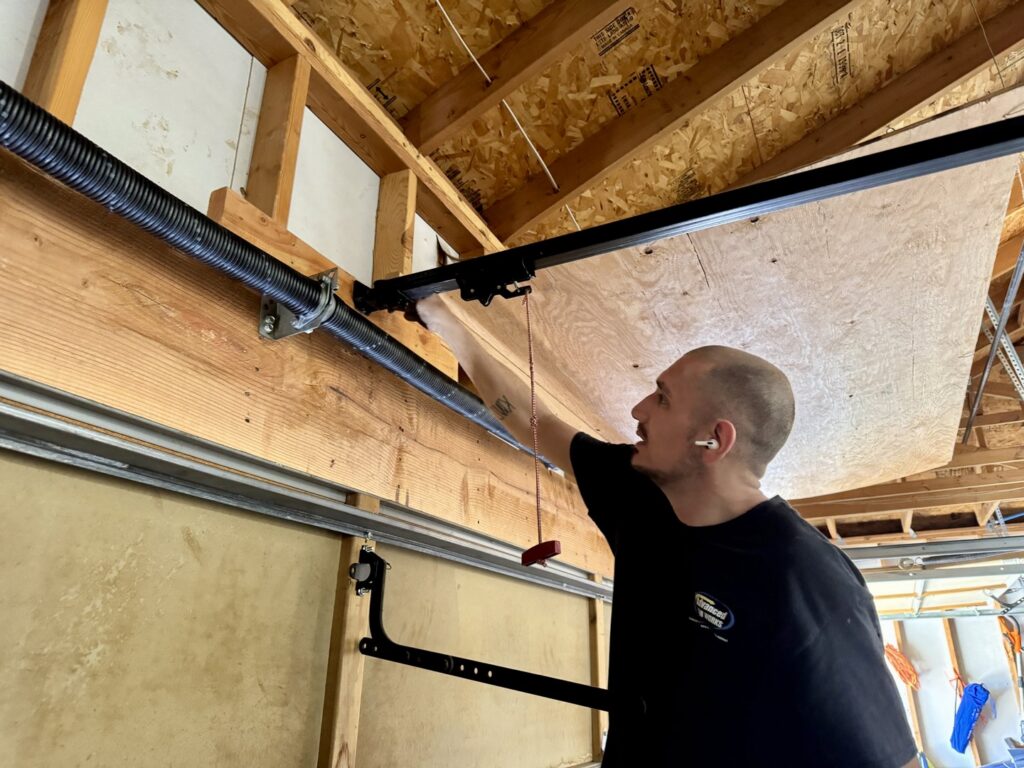 A technician repairing a garage door spring system for Advanced Door Works in Highlands Ranch, CO