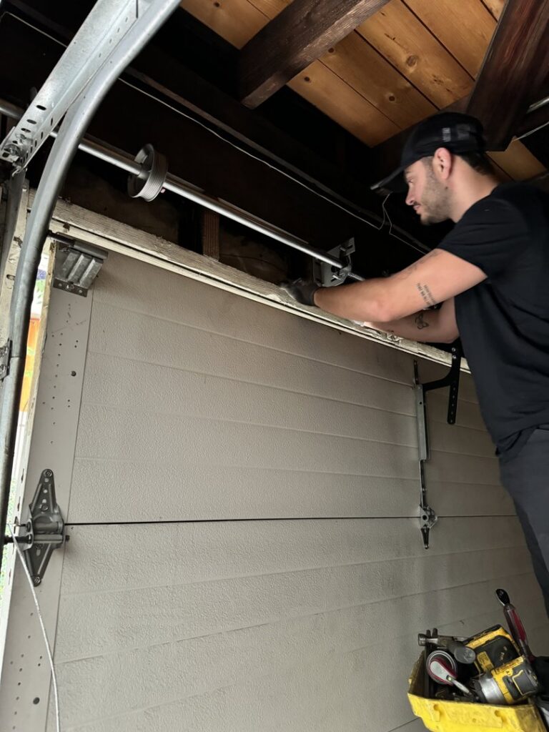 A professional technician repairing the spring mechanism of a garage door, a service provided by Integrity Garage Door Repair in Clearwater, FL.