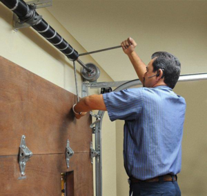 A technician repairing a garage door torsion spring system at Olympus Garage Door Repair in Tempe, AZ.