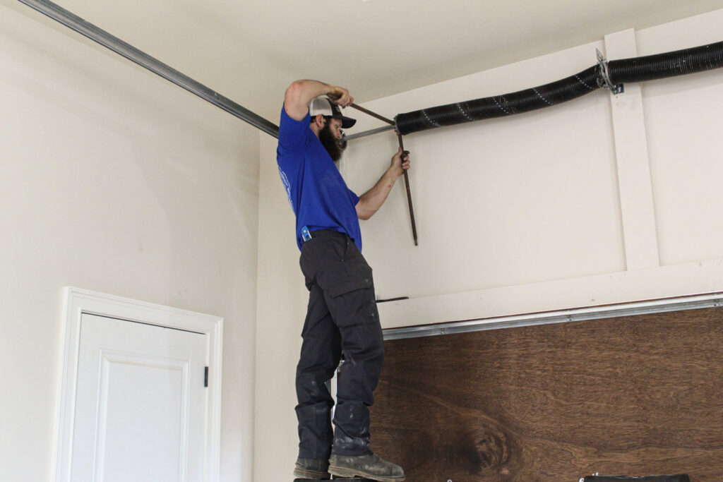 A professional technician repairing a garage door spring for Signature Garage Doors in Huntsville, AL.