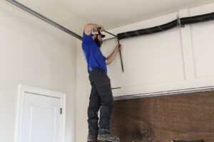 A professional technician repairing a garage door spring for Signature Garage Doors in Huntsville, AL.