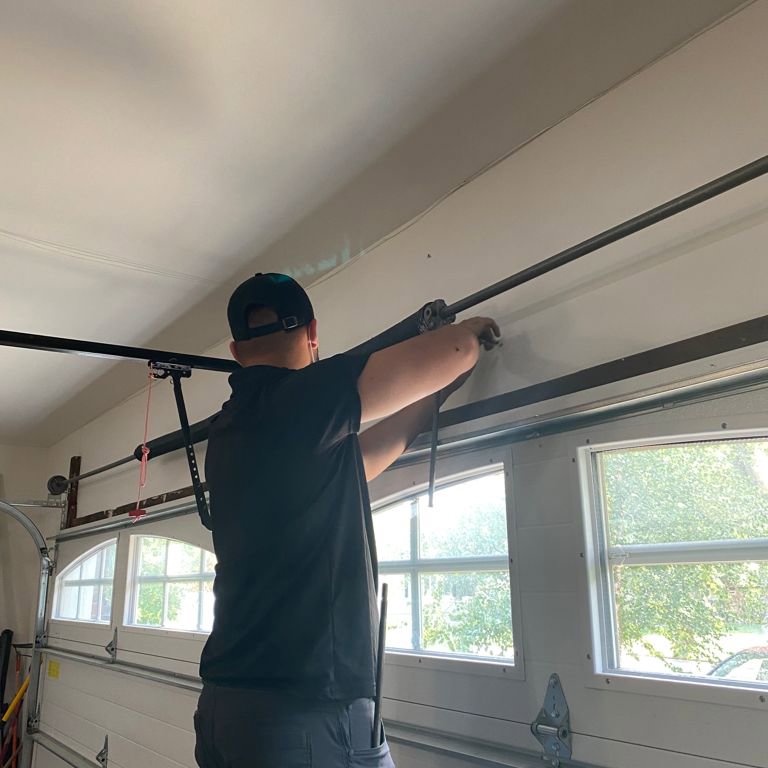 A technician repairing a garage door spring and track system for The Region's Garage Door Repair in Hammond, IN.