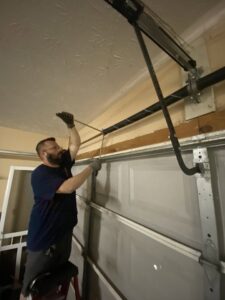 A technician from Foothills Garage Door Service LLC repairing garage door springs in Louisville, TN.