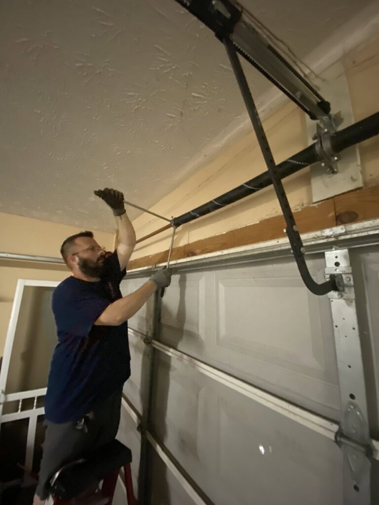 A technician from Foothills Garage Door Service LLC repairing garage door springs in Louisville, TN.
