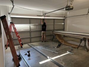 A Geaux Overhead Door technician repairing garage door springs and mechanism inside a residential garage in West Monroe, LA.