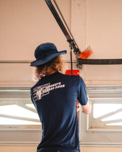 A technician from Smokey's Garage Door Company repairing garage door springs in Glendale, AZ.