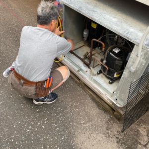 A technician repairing an outdoor HVAC unit for Doctor Air HVAC in Philadelphia, PA.