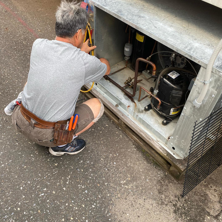 A technician repairing an outdoor HVAC unit for Doctor Air HVAC in Philadelphia, PA.