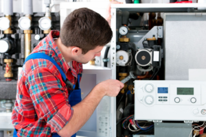 A technician from McTeer's Heating & Cooling in Salisbury, MD, repairing an indoor boiler or furnace unit with a wrench.