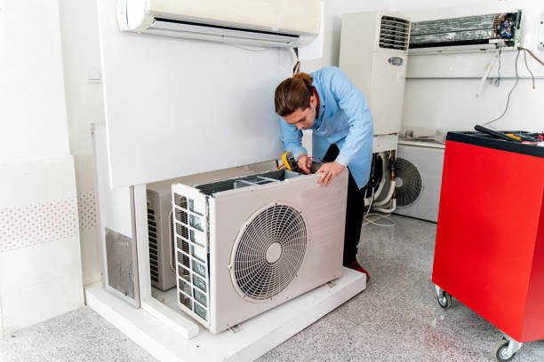 A technician repairing an indoor HVAC unit for Controlled Climate Solutions in Decatur, AL.