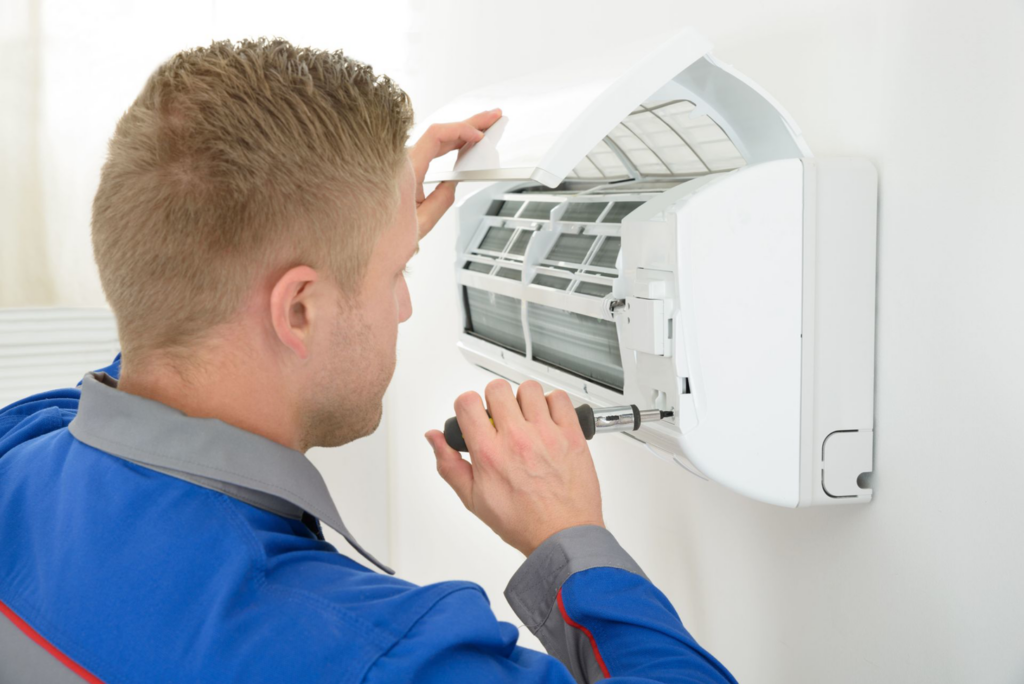 A technician repairing an indoor mini-split air conditioning unit, a service offered by APM Heating and Air Conditioning in Columbia, MO.