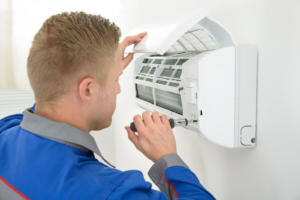 A technician repairing an indoor mini-split air conditioning unit, a service offered by APM Heating and Air Conditioning in Columbia, MO.