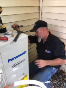 A technician repairing an outdoor Panasonic Inverter HVAC unit for Automatic Heating And Air Inc. in Fargo, ND