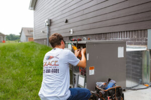 A technician repairing an outdoor HVAC unit, showing internal wiring, for Grace Heating & Air in Clarksville, TN.