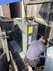 A Tek-Aire Services Inc. technician repairing an outdoor HVAC condenser unit at a residential property in Columbia, SC.