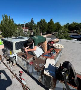 A Gagles Heating technician repairing a commercial rooftop HVAC unit in Salem, OR.