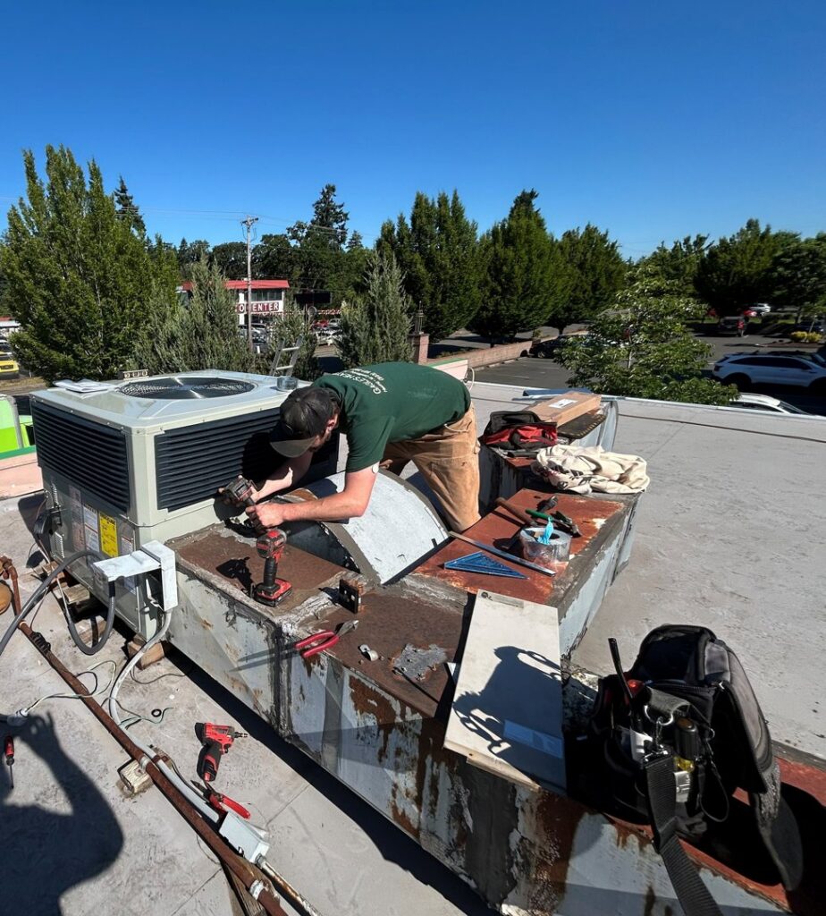 A Gagles Heating technician repairing a commercial rooftop HVAC unit in Salem, OR.