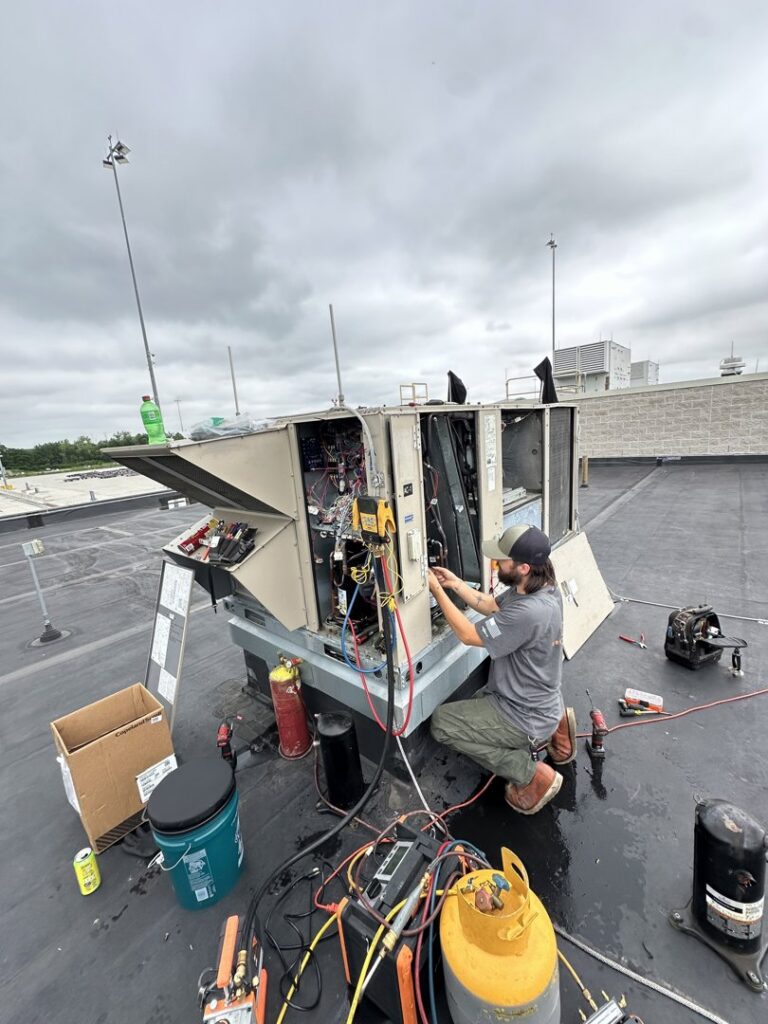 A technician repairing a large rooftop HVAC unit with tools and equipment for Green Mechanical LLC in Philadelphia, PA.