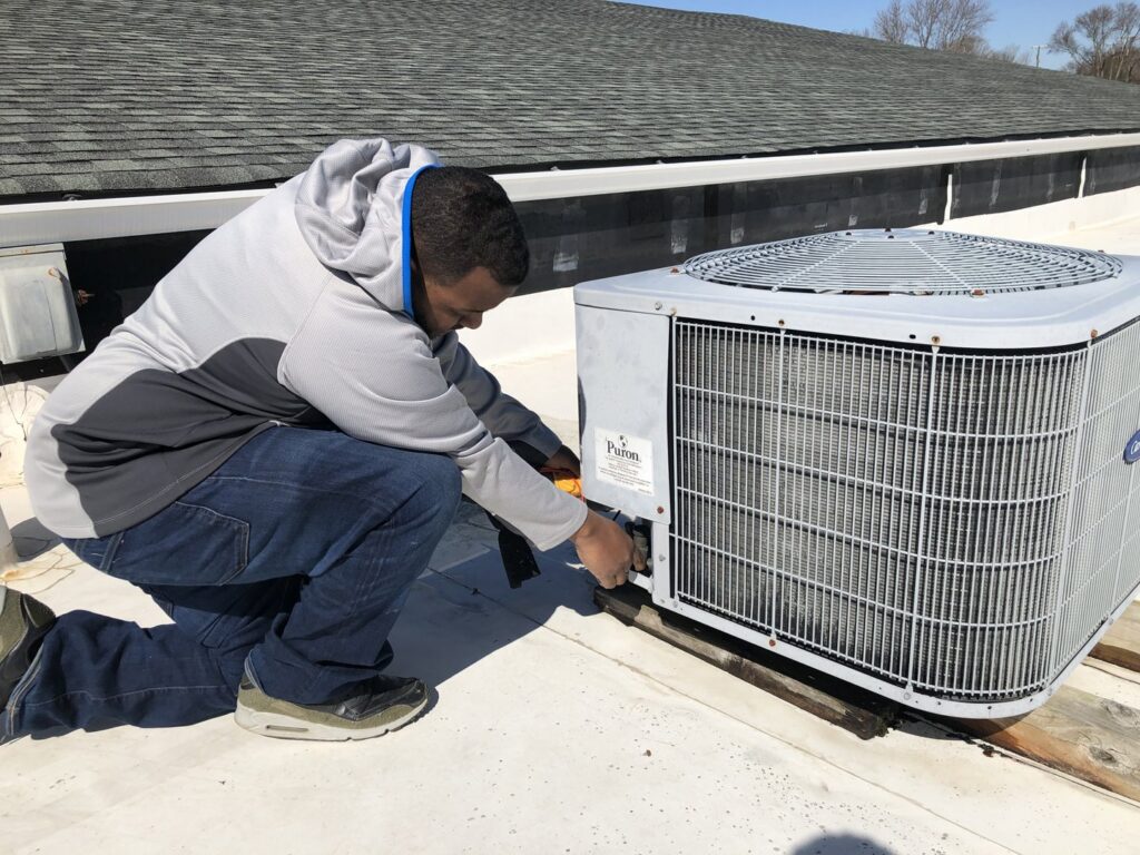 A Nashville Solutions technician repairing an outdoor HVAC unit on a rooftop in Nashville, TN