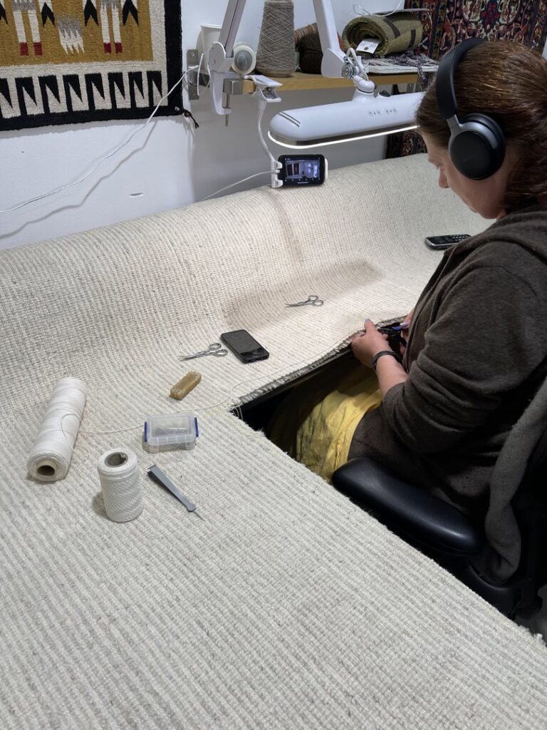 A skilled technician meticulously repairing the edges of a rug at Renaissance Rug Cleaning Inc. in Portland, OR.