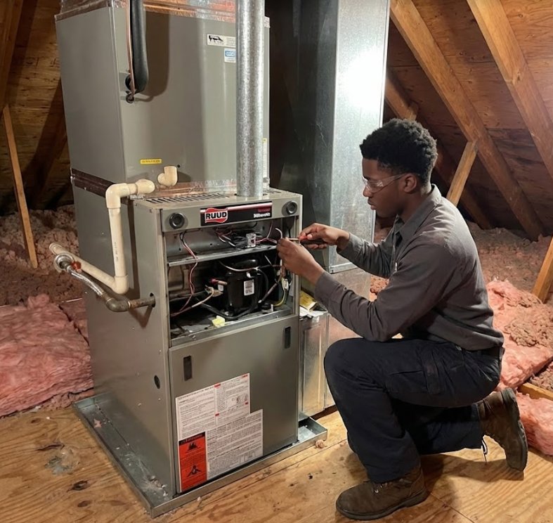 A technician repairing a Ruud HVAC unit in an attic space for RESTQ HVAC Repairs & Services in Rockville, MD.
