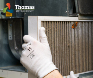 A technician replacing a dirty HVAC air filter for Thomas Service Company in Huntsville, AL
