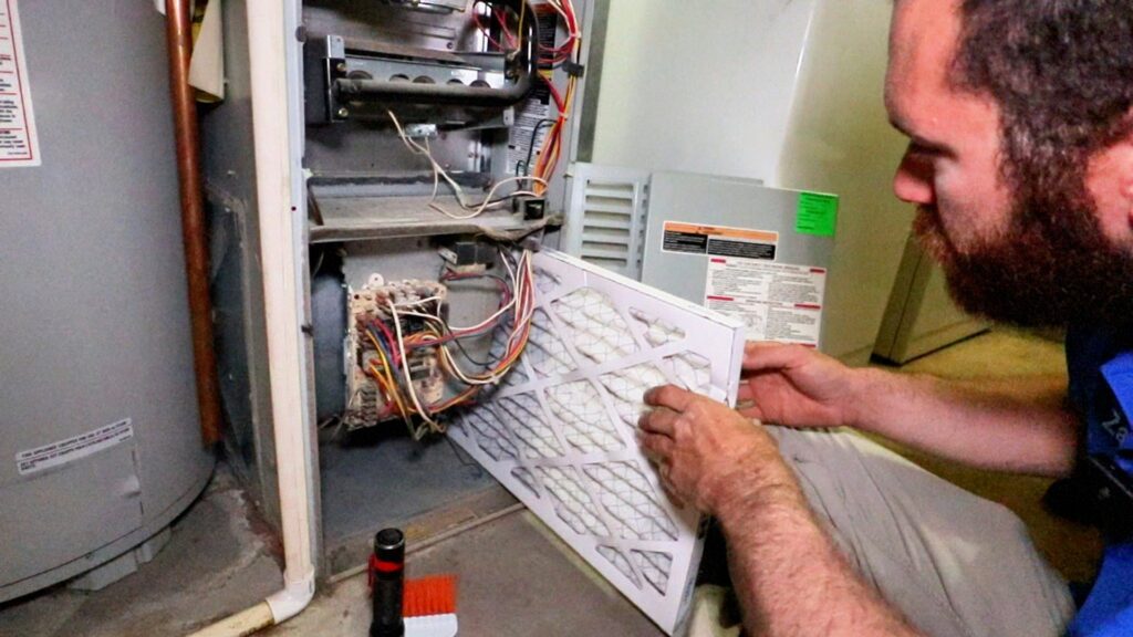 A technician replacing a dirty furnace air filter during a service call by Utah Mechanical Heating and Air Conditioning in South Ogden, UT.