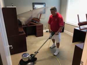 A technician from Johns Creek Carpet Cleaner using a rotary scrubber on an office carpet in Johns Creek, GA.