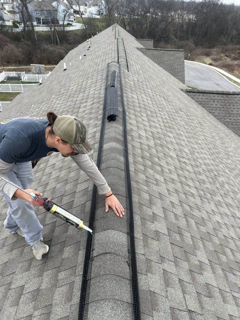 A technician sealing a roof ridge vent with mesh for wildlife exclusion and prevention by Elite Wildlife Removal and Prevention in Nashville, TN.
