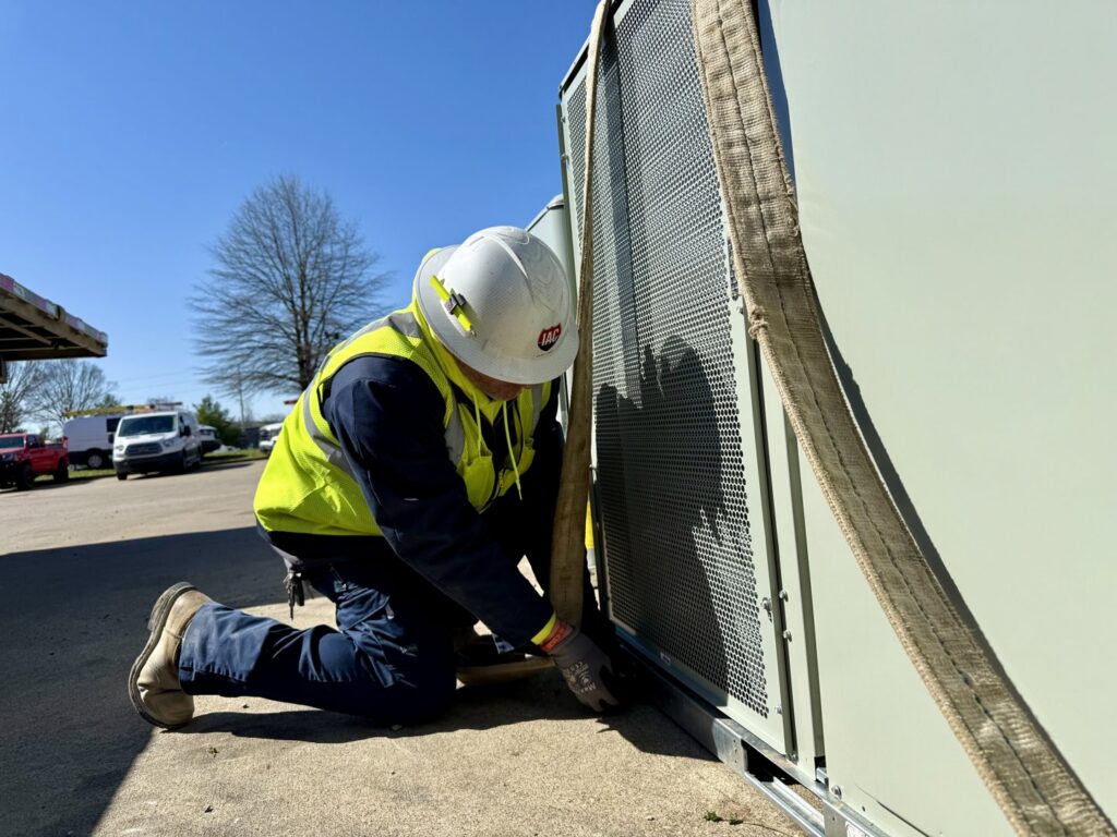 An Interstate AC technician securing a large HVAC unit with straps, preparing for installation in Nashville, TN.