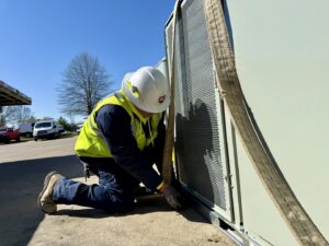 An Interstate AC technician securing a large HVAC unit with straps, preparing for installation in Nashville, TN.