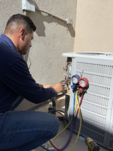 A technician servicing an outdoor AC condenser unit with gauges for Lone Star Mechanical in El Paso, TX.