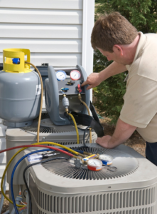 A technician servicing an outdoor air conditioning unit with gauges and a refrigerant tank for Custom Heating & Air Conditioning - Nampa in Nampa, ID.