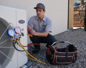 A technician using gauges and tools to service an outdoor air conditioning unit for S&S Mechanical in St. George, UT
