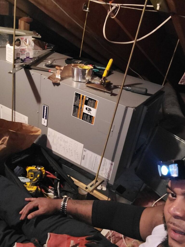 A technician servicing an attic air handler unit for Will Power Refrigeration Co in Yonkers, NY.