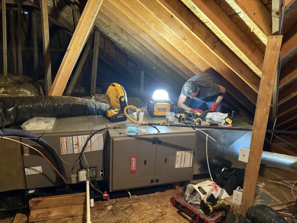 A technician from 4-BIS Solutions HVAC and Home Maintenance servicing a Coleman HVAC unit in an attic in Columbia, MO.