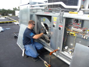 An AireCom HVAC technician servicing a commercial rooftop HVAC unit in Columbus, OH.