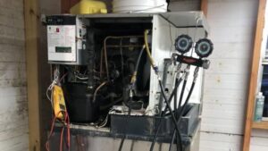A technician servicing a commercial ice machine with gauges attached, performed by Merriam Elite Solutions in Satsuma, AL.