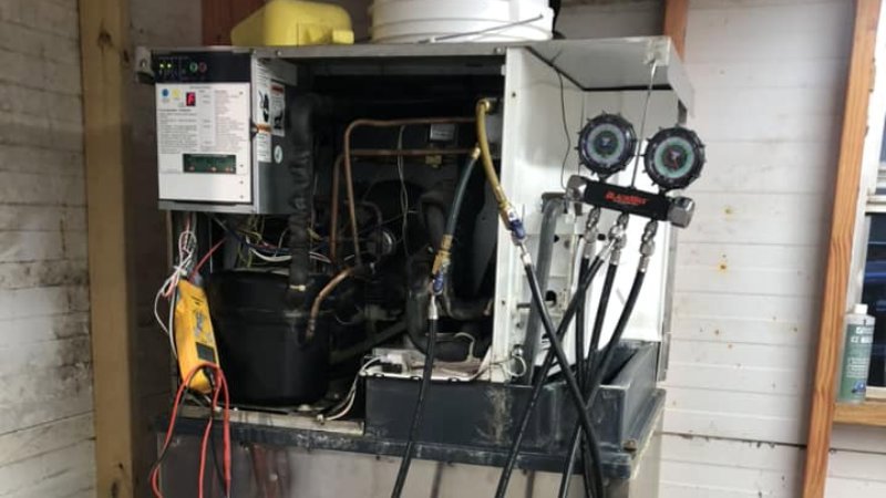 A technician servicing a commercial ice machine with gauges attached, performed by Merriam Elite Solutions in Satsuma, AL.