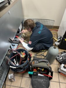 A Mr. Fridge technician servicing a commercial refrigeration unit with tools and equipment in Seattle, WA.