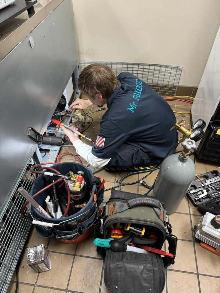 A Mr. Fridge technician servicing a commercial refrigeration unit with tools and equipment in Seattle, WA.