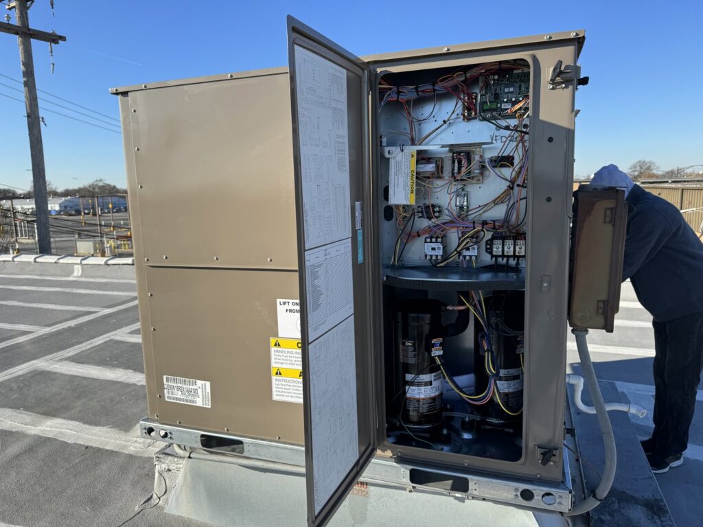 A technician servicing an open commercial rooftop HVAC unit for Etek Refrigeration Heating and Cooling, Inc. in Chicago, IL.