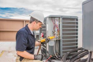 A technician in a hard hat servicing a commercial rooftop HVAC unit for Millard Heating & Cooling in Elkhorn, NE.