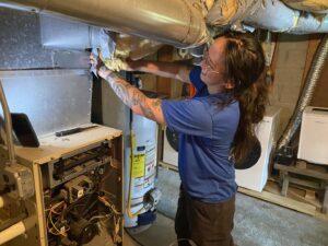 A Blue Bear Plumbing, Heating, & Air technician servicing a furnace unit in Norwell, MA.