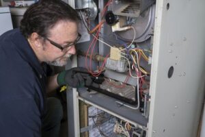 A technician servicing a furnace with the panel open for Daniels HVAC Philadelphia LLC in Philadelphia, PA.