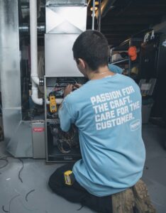 A Nimmer Heating & Air Conditioning technician servicing a furnace or air handler unit in Milwaukee, WI.