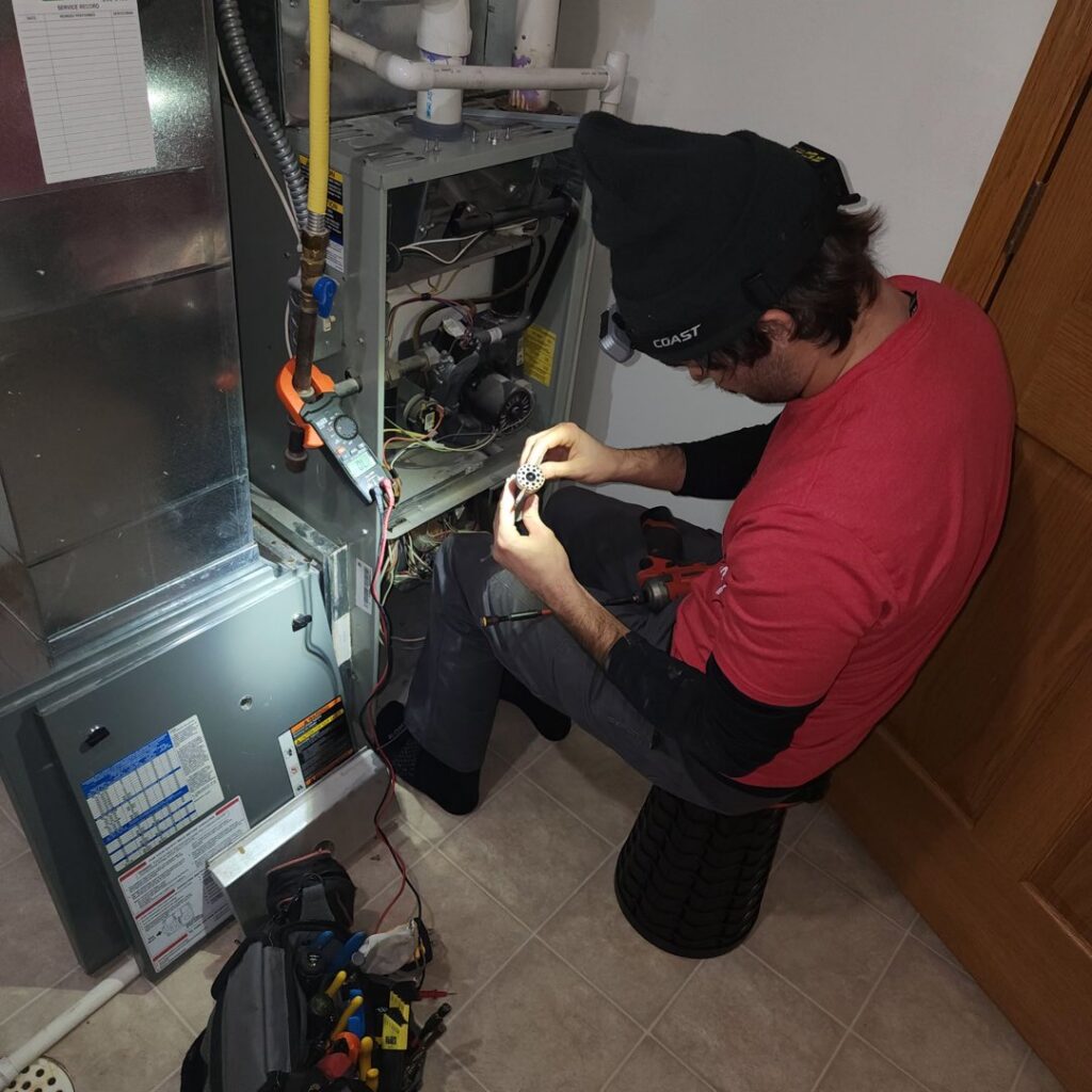 A technician performing maintenance on a residential furnace for Precision Heating & Air Conditioning in Royersford, PA