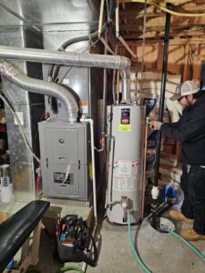 A technician servicing a residential furnace and water heater system for Henry Refrigeration & Hvac Utah in Ogden, UT.